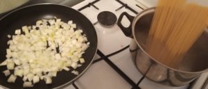 Zeszklić cebulę i ugotować makaron lub ryż